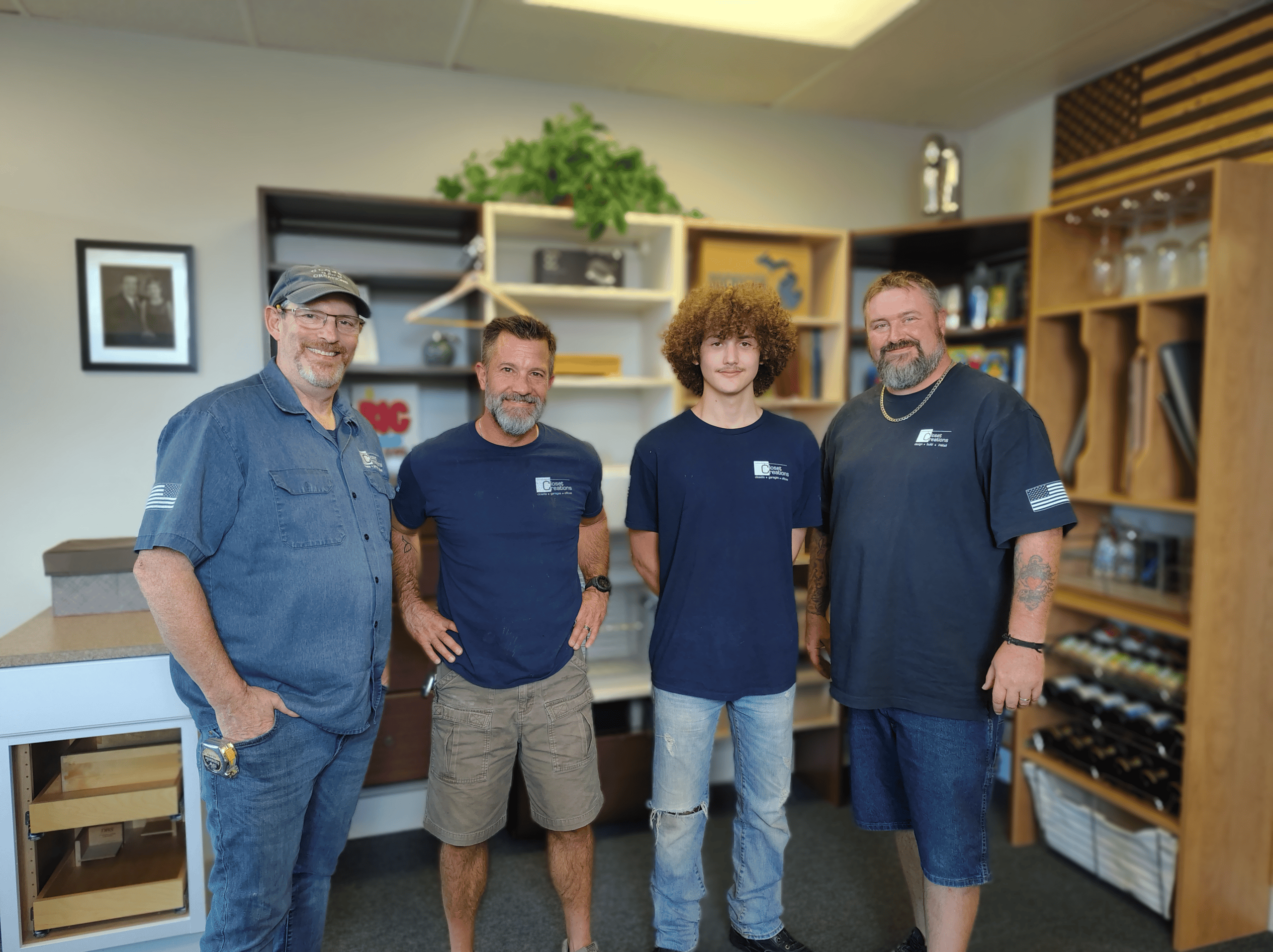 Four team members in a custom closet showroom, showcasing professional closet design and installatio.
