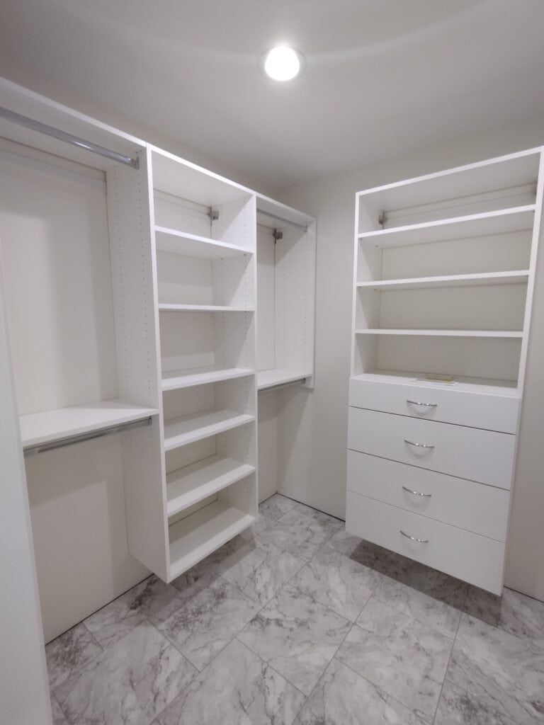 Custom white closet with shelves and drawers for organized storage.