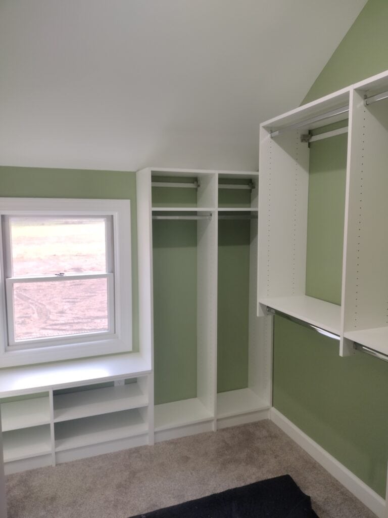 Custom closet organization with shelves and hanging space in a light green room.