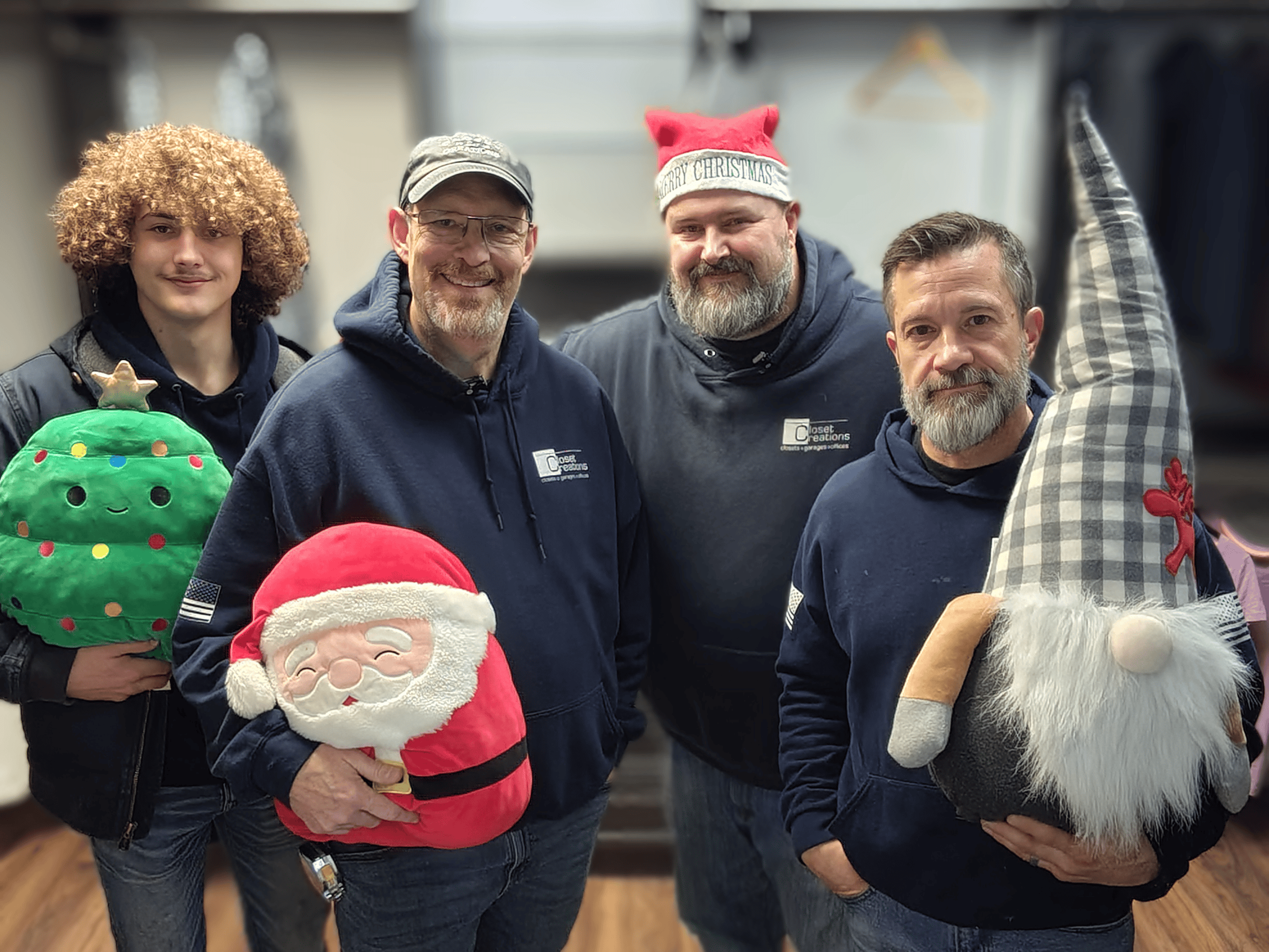 Festive team members holding holiday decorations and gnomes at a Christmas event.