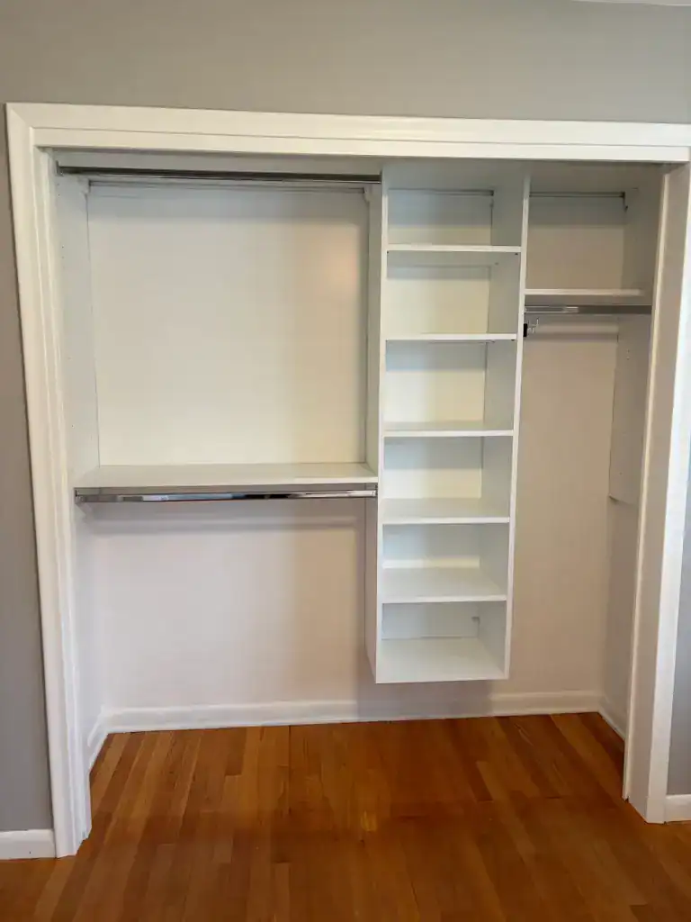 Spacious white closet with shelves and hanging rods for organized storage solutions.